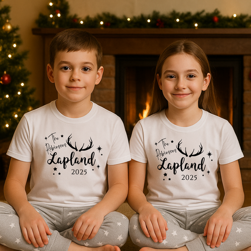 Lapland holiday matching . pyjamas sets perfect for festive family photos. Two children wearing personalised matching white t-shirts with 'The  Lapland 2025' text in a festive setting.