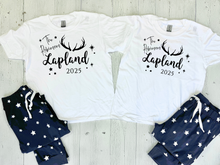 Load image into Gallery viewer, Two white t-shirts with &#39;The Robinsons Lapland 2025&#39; text and navy pajama sets on a light wooden surface. Cosy Christmas Lapland pajamas with personalised Lapland travel PJs