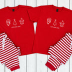 A matching Christmas pajama set laid flat on a white wood plank background, featuring two red short-sleeve shirts with white holiday graphics and text reading 'LAPLAND 2026,' paired with red-and-white striped pants.